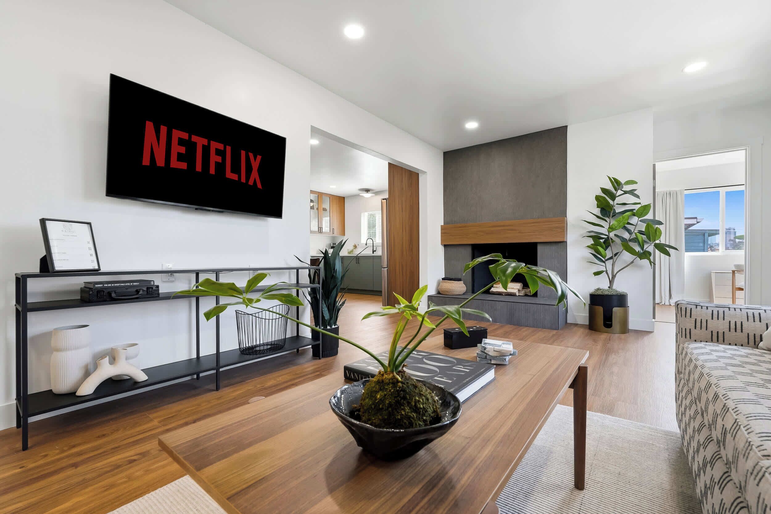 Una sala moderna con un cartel de Netflix, chimenea y vistas de la ciudad.