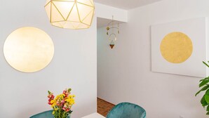 Ein Zimmer mit einem geometrischen Lichtarmaturen, einer runden Wanddekoration, einer Wanduhr und einer Vase mit Blumen.