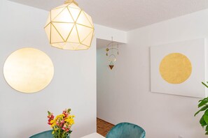 Ein Zimmer mit einem geometrischen Lichtarmaturen, einer runden Wanddekoration, einer Wanduhr und einer Vase mit Blumen.