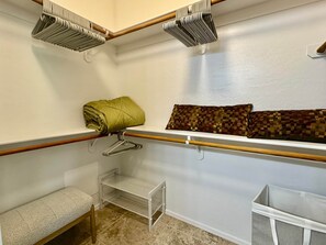Ein Schrank mit Regalen, einer Sitzbank und einer Kleiderstange.