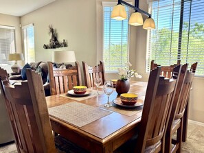A dining area with a wooden table, chairs, and a vase with flowers. - Vistoso Condo #226C (Oro Valley)