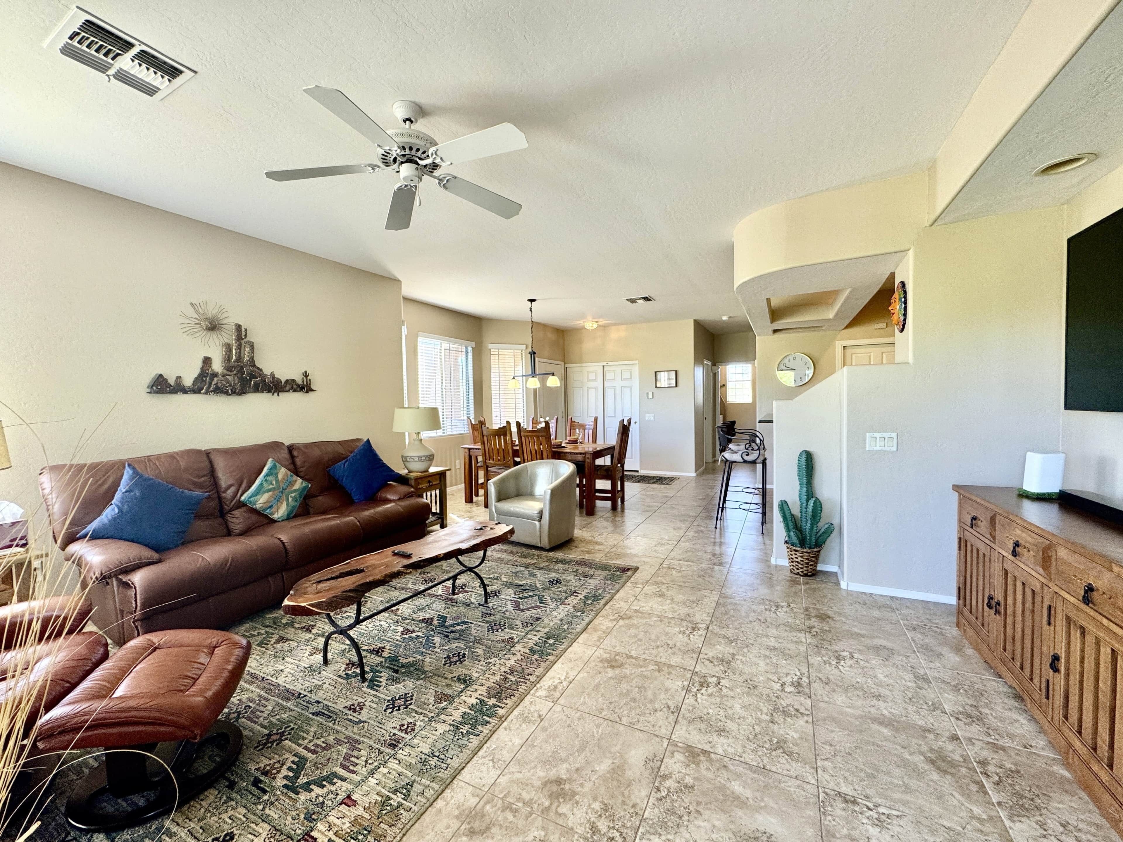 A spacious living room with a brown leather sofa, a coffee table, and a patterned rug.