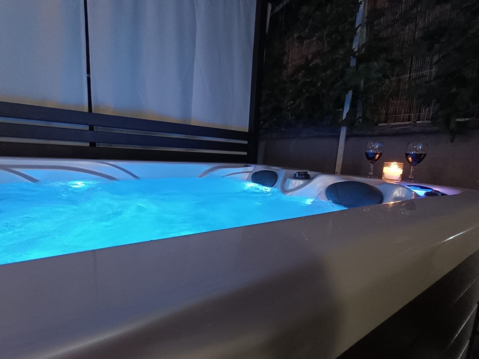 A hot tub with a candle and two glasses of wine.