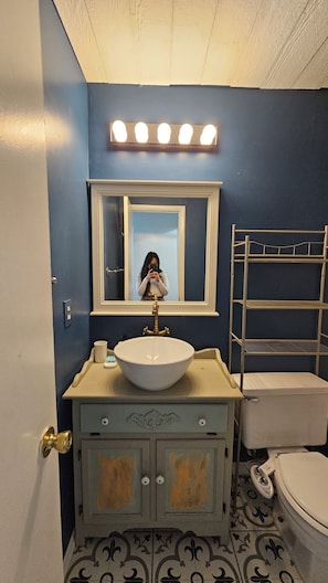 A bathroom with a vanity, sink, mirror, and a toilet.