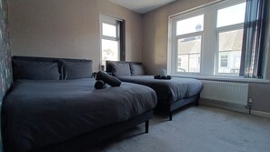 A bedroom with two beds, large windows, and a radiator. - Cosy Hot Tub Hideaway w/Private Garden (Cardiff)