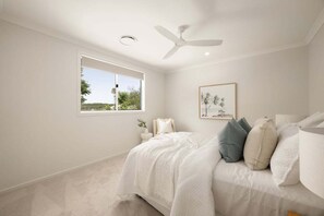 Ein Schlafzimmer mit einem Bett, einem Deckenventilator, einem Fenster und einem gerahmten Bild an der Wand.