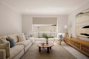 Ein modernes Wohnzimmer mit einer Couch, einem Couchtisch und Blick auf einen Balkon.