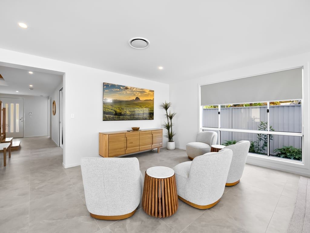 A modern living room with a sofa set, a wooden cabinet, and a large window.