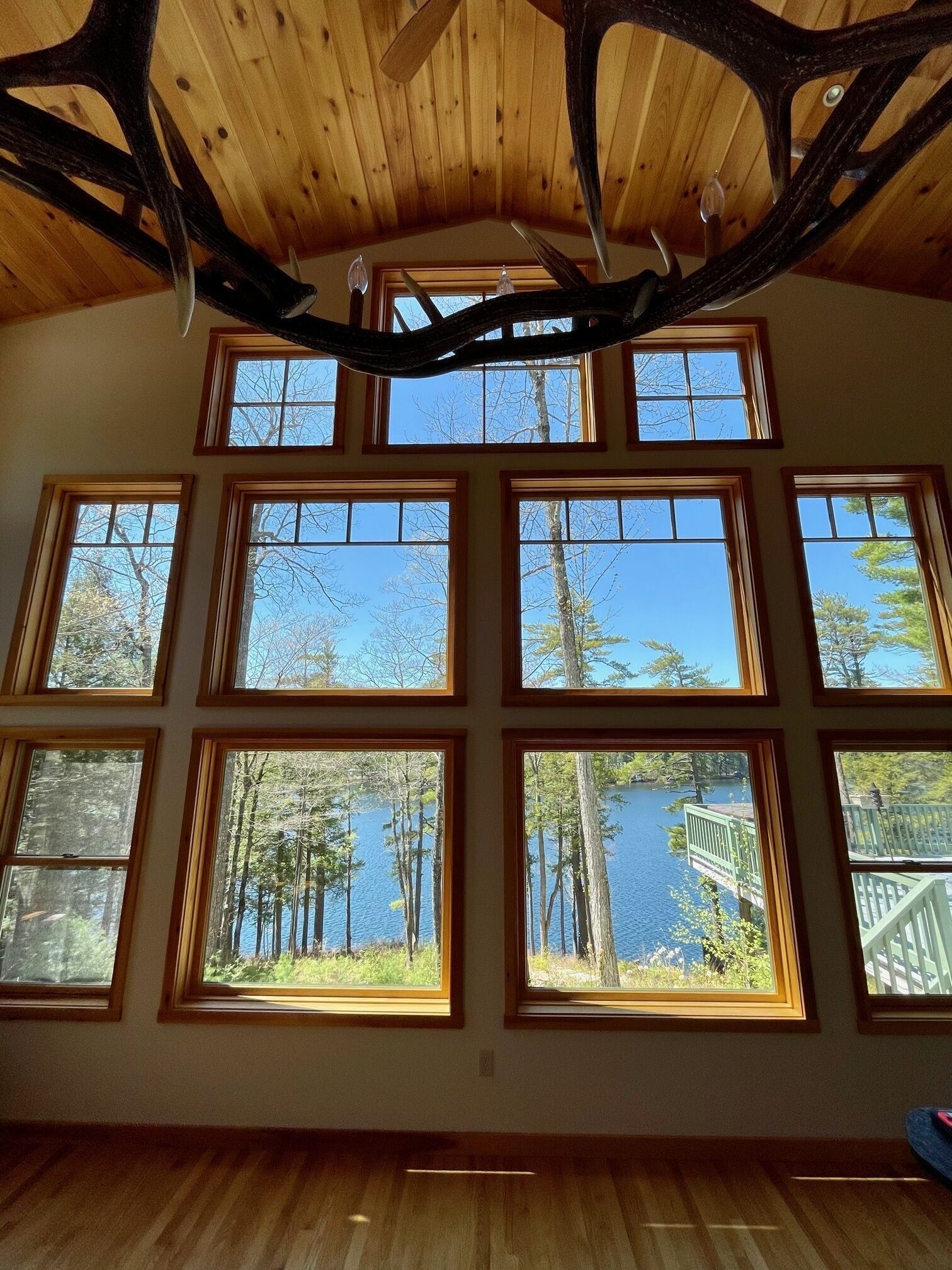 A room with multiple windows offering views of a lake and trees.