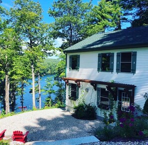 A two-story house with a porch, a gravel driveway, and a lake view.