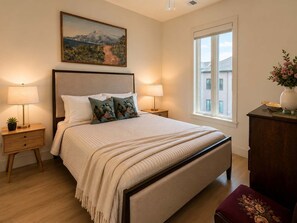 Ein Schlafzimmer mit einem Bett, zwei Nachttischen, einem Fenster und einem Bild an der Wand.