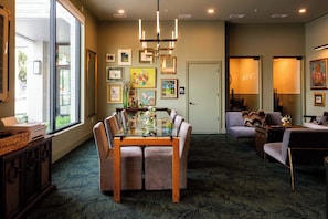 A dining area with a glass table and chairs, a vase with flowers, and framed pictures on the wall. - The Jardin Meadow Suite | Near Downtown (Savannah)