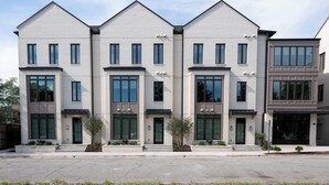 Ein modernes, mehrgeschossiges Wohngebäude mit einer symmetrischen Fassade, großen Fenstern und einem zentralen Eingang.
