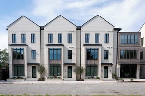 Ein modernes, mehrgeschossiges Wohngebäude mit einer symmetrischen Fassade, großen Fenstern und einem zentralen Eingang.