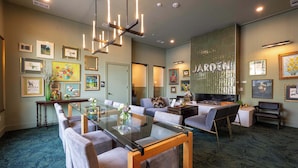 Eine moderne Hotellobby mit einem Esstisch mit Glasplatte, bequemen Sitzgelegenheiten und einer großen Wanddekoration.