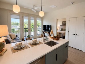 Een moderne keuken met een groot schiereiland, een zithoek met een bank, en een balkon met een televisie.
