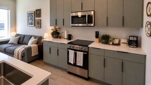 Una cocina moderna con armarios grises, una estufa de acero inoxidable y un microondas.