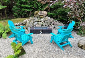 A seating area with two turquoise chairs and a table, surrounded by a rock formation and greenery.