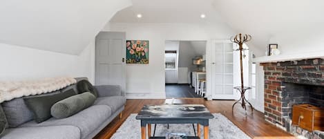 Uma sala de estar moderna com um sofá cinzento, uma mesa de centro e uma lareira.