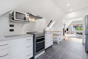 Een moderne keuken met inbouwapparatuur, een eethoek met een houten tafel en uitzicht op de omgeving door een groot raam.