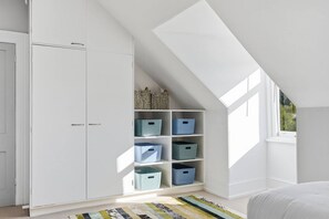 A room with a sloped ceiling, white wardrobe, and blue storage bins. - Hill Street Hideaway (West Hobart)