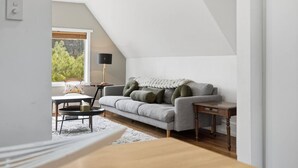 Ett modernt vardagsrum i loftstil med en grå soffa, ett litet runt bord och en lampa.