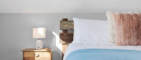 A bedroom with a bed, a nightstand with a lamp, and a wooden headboard.