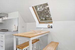 A kitchen with a wooden table and bench, a window with a view, and a white countertop. - Hill Street Hideaway (West Hobart)