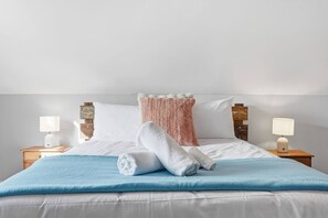 Een hotelkamer met een bed, twee nachtkastjes en twee lampen.