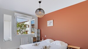 Een slaapkamer met een bed, nachtkastje, radiator, raam en een hanglamp.