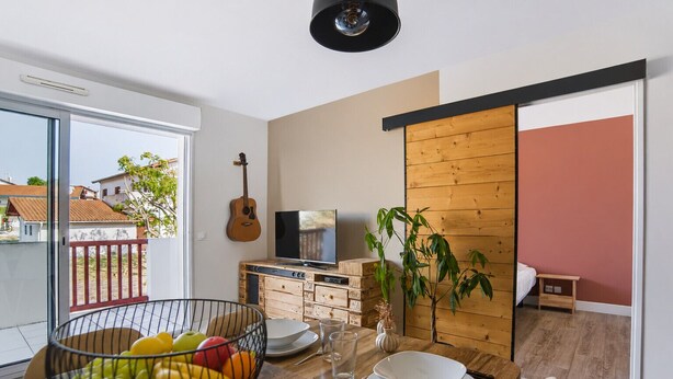 Een moderne woonkamer met een eethoek, een televisie en een gitaar.