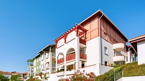 Een meerlaags hotel met balkons, een plat dak en een helderblauwe lucht.