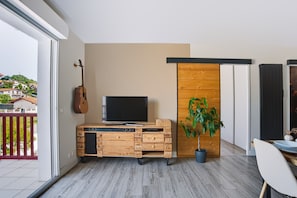 Een moderne woonkamer met een televisie, een gitaar en een plant.