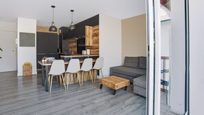 Een moderne keuken met een eethoek, een grijze bank en een houten salontafel.