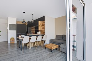 A modern kitchen with a dining area, a grey sofa, and a wooden coffee table. - Appartement Teilleria - Welkeys (Hendaye)