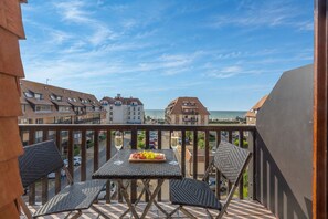 Ein Balkon mit Tisch und Stühlen mit Blick auf Strand und Gebäude.