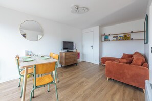 Ein modernes Wohnzimmer mit Essbereich, einem Fernseher und einer Bücherwand mit Büchern.