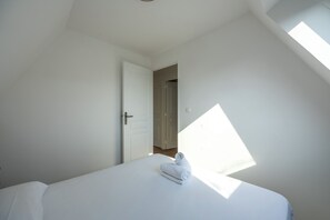 A bedroom with a bed, a door, and a skylight. - Le Balcon du Grand Cap - vue mer - Welkeys (Villers-sur-Mer)