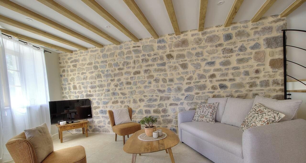A living room with a stone wall, a sofa, a coffee table, and a television.