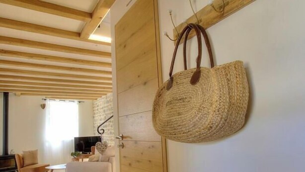 Een kamer met een houten plafond, een wandlamp en een rieten mand aan de wand.