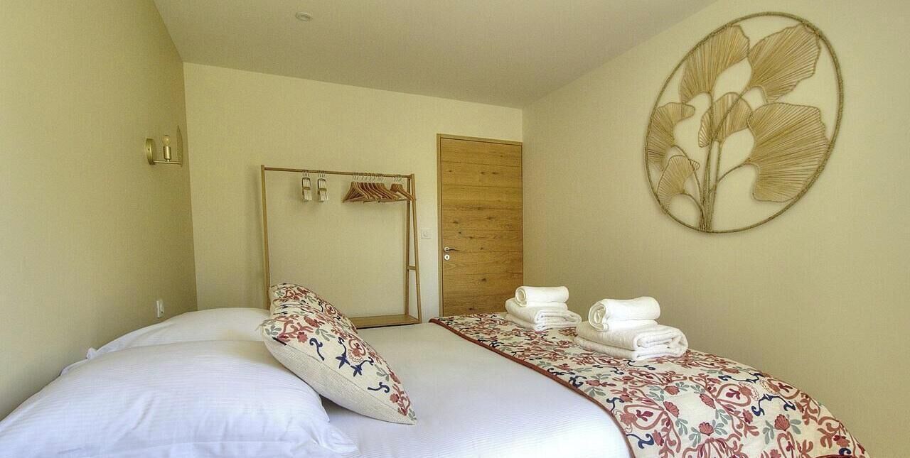 A bedroom with a bed, a wooden door, and a wall-mounted towel rack.
