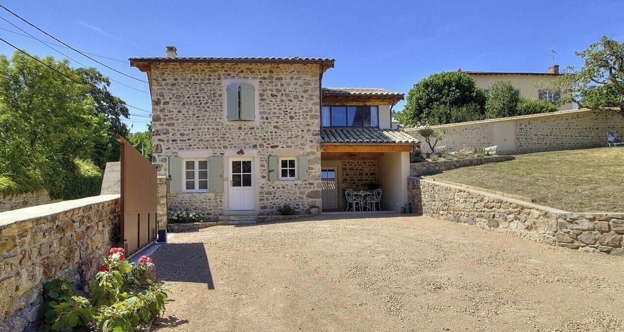 A stone building with a gravel driveway and a small patio area.