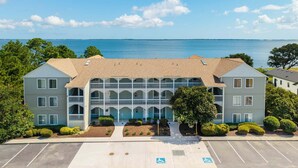 A waterfront building with a central courtyard, multiple balconies, and a parking lot with handicapped accessibility. - RSC203 - Wander Mint Soundfront condo with sunset views (Manteo)