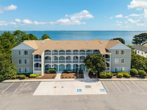 A waterfront building with a central courtyard, multiple balconies, and a parking lot with handicapped accessibility. - RSC203 - Wander Mint Soundfront condo with sunset views (Manteo)