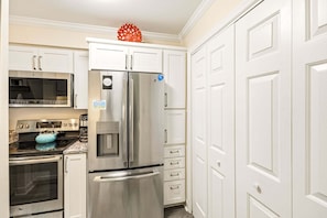 A kitchen with a stainless steel refrigerator, a microwave, an oven, and a water dispenser. - RSC203 - Wander Mint Soundfront condo with sunset views (Manteo)