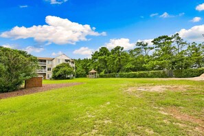 A two-story residential building with a fenced yard, a gazebo, and mature trees. - RSC203 - Wander Mint Soundfront condo with sunset views (Manteo)
