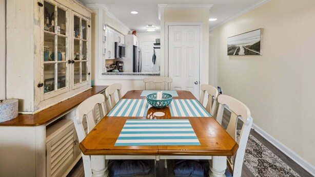 A dining area with a wooden table, striped placemats, and white chairs. - RSC203 - Wander Mint Soundfront condo with sunset views (Manteo)