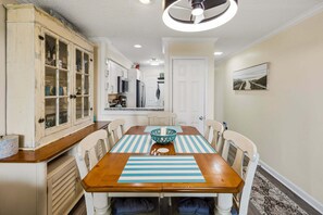 Een eetruimte met een houten tafel, geribbelde placemats en witte stoelen.