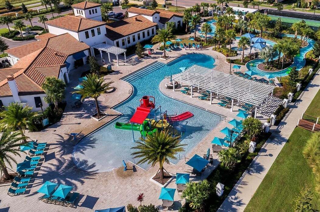A resort with a large swimming pool, a water slide, and lounge areas with umbrellas.