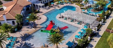 A resort with a large swimming pool, a water slide, and lounge areas with umbrellas.